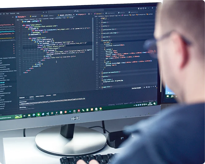 Dwie osoby pracują nad UX/UI, tworząc makiety stron. Na stole są próbki kolorów, co sugeruje także projektowanie wizualne.